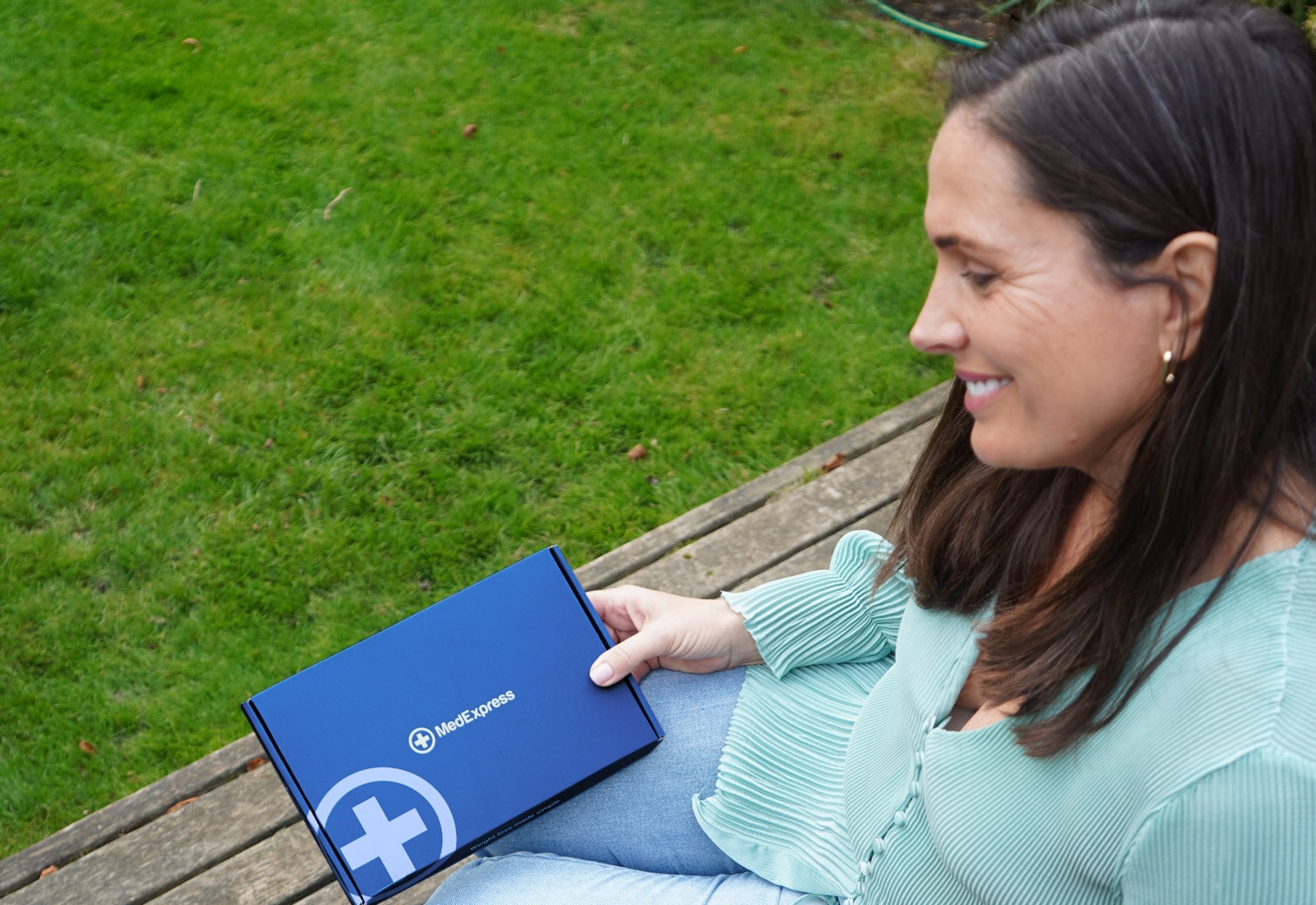 Woman sitting outdoors with a MedExpress delivery box